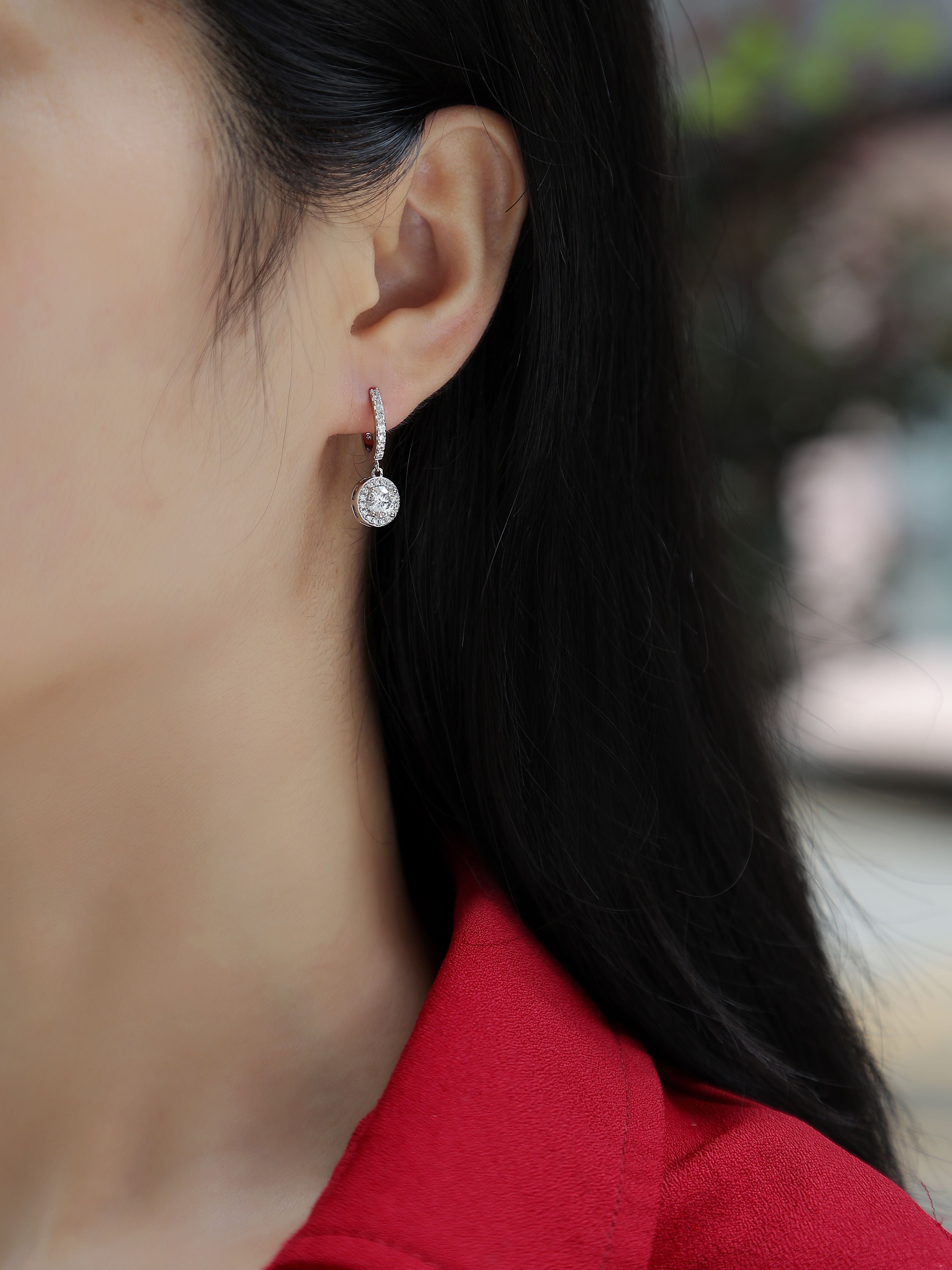 Close-up of a person wearing a diamond earring with a blurred background
