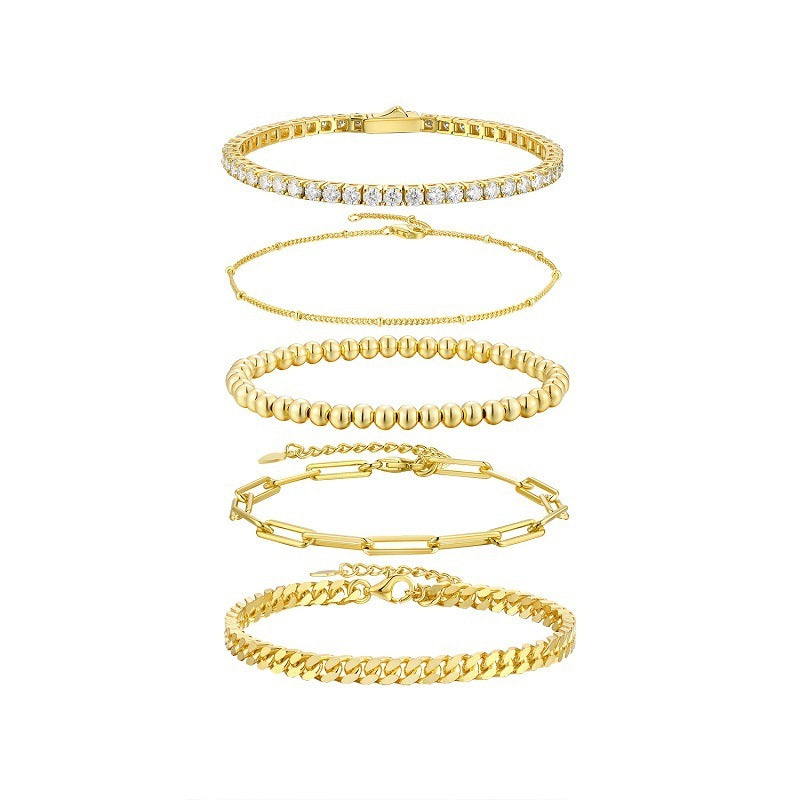 Set of five gold bracelets on a white background