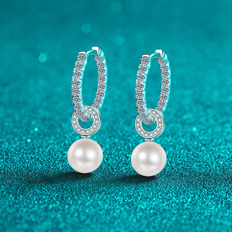 Pearl earrings with silver hoop designs on a teal background