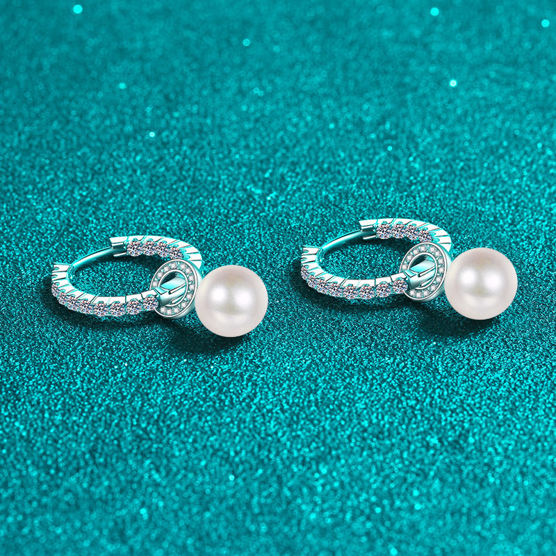 Pair of pearl earrings on a teal glittery background